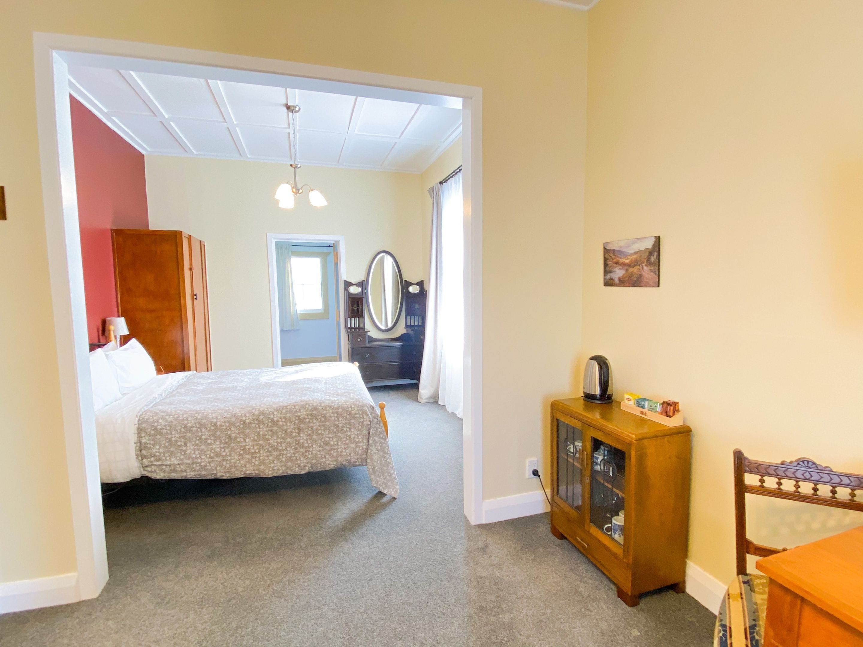 A hotel room with a bed, a dresser, a mirror, and a cabinet.