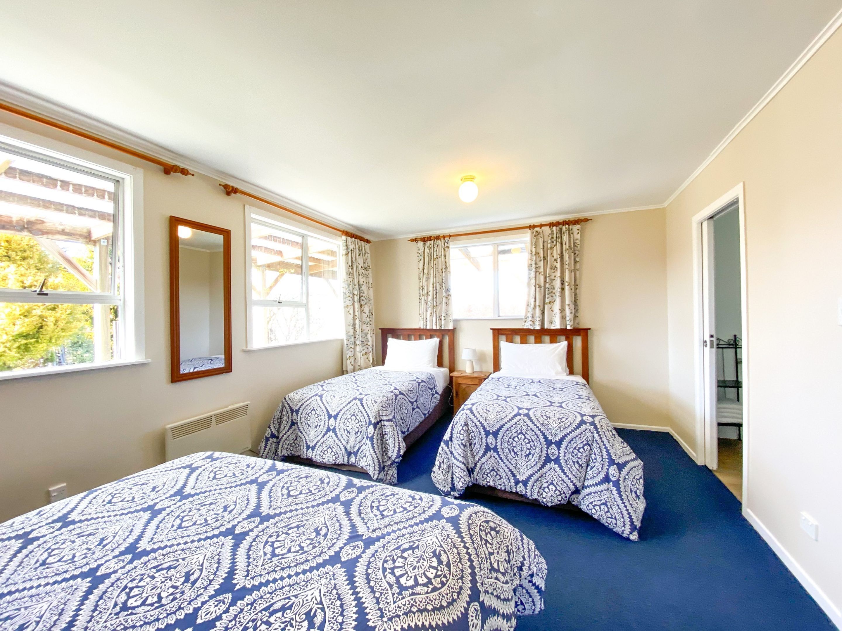 A room with two beds, a mirror, and a window.