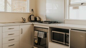 A modern kitchen with a built-in oven, microwave, and gas stove. - Tongariro Crossing Lodge (National Park Village)