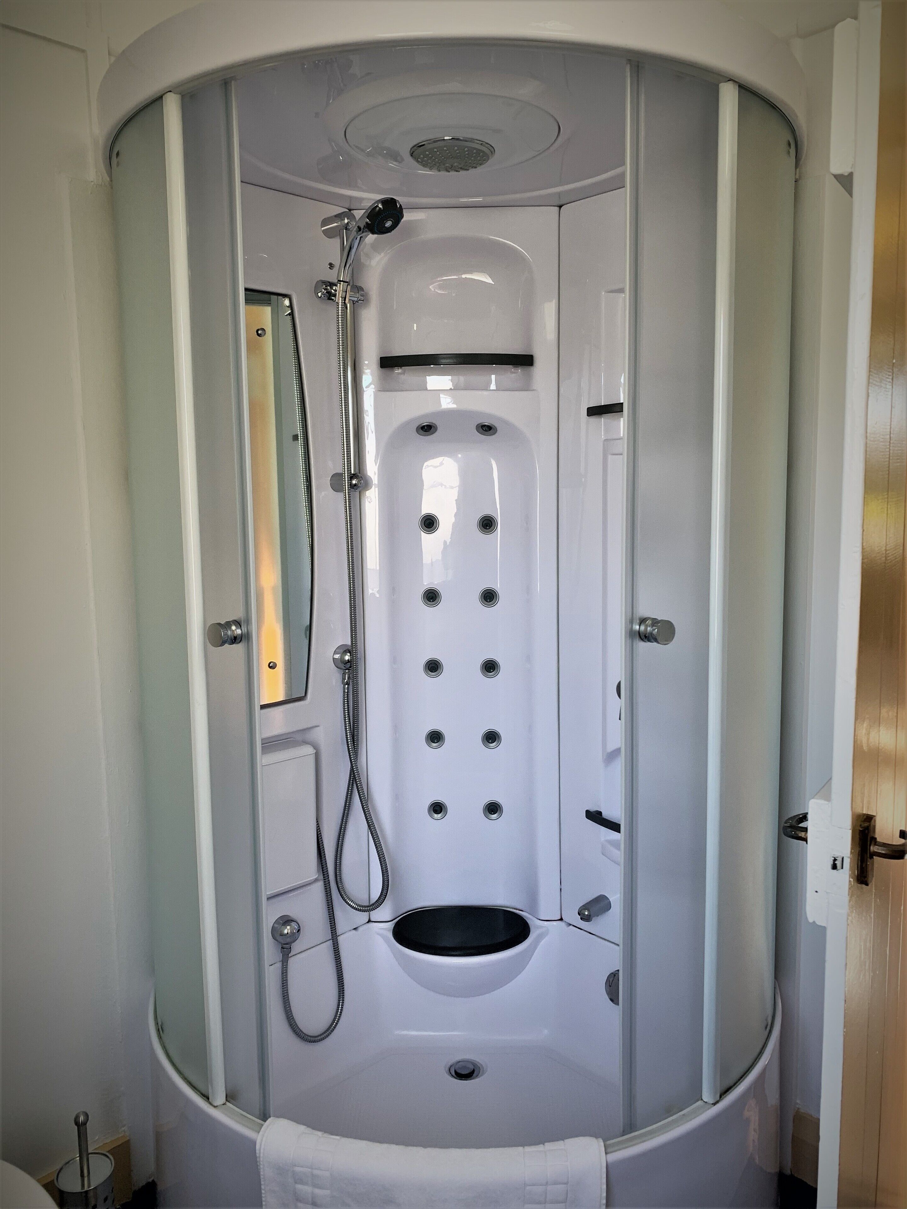 A modern, enclosed bathroom with a built-in shower, a toilet, and a sink.