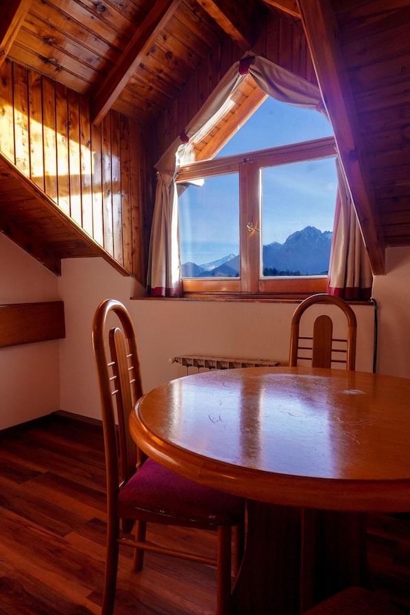 Enjoy a mountain view from the large window in this room, featuring a round table and two comfortable chairs.