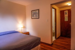 Cozy retreat with a neatly made bed, bedside table, and framed picture.