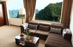 Una sala moderna con un conjunto de sofá, una mesa de centro con objetos decorativos y vistas a un paisaje montañoso a través de grandes ventanales.
