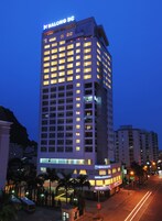 Un hotel de gran altura con varios pisos, ventanas iluminadas y un letrero llamativo en la parte superior.