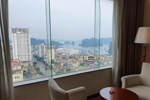 Habitación con un amplio ventanal que ofrece vistas panorámicas de la ciudad, dos sillas y una pequeña mesa.