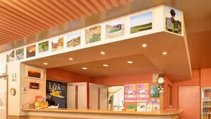 Un mostrador de recepción con detalles de madera, un reloj y una pared con cuadros enmarcados.