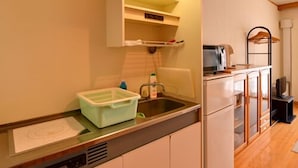 Una cocina compacta con microondas integrado, un fregadero y un pequeño armario.