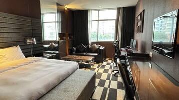 Une chambre d’hôtel moderne avec un grand lit, un canapé, une télévision et un sol à carreaux.