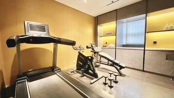 A hotel gym with a treadmill, stationary bike, and weights.
