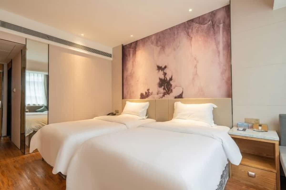 A hotel room with a large bed, a nightstand, and a wall-mounted artwork.
