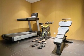 A gym with a treadmill, an elliptical, and a bench. - Marco Polo Holiday Hotel (Nanning)