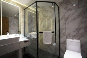 A modern bathroom with a glass-enclosed shower, a white toilet, and a marble-tiled wall.