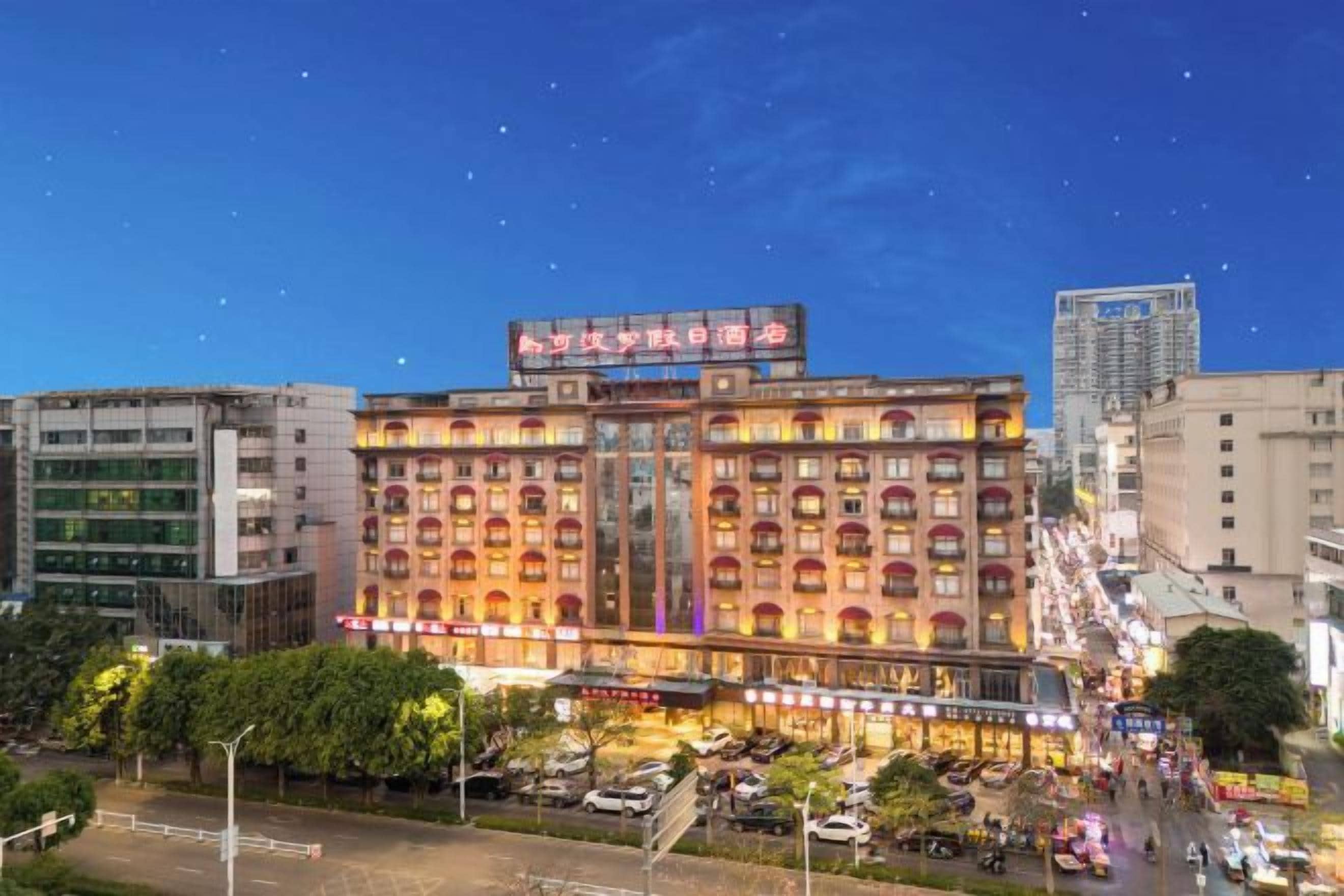 Un hotel de varios pisos con un letrero llamativo y un área de estacionamiento al frente.