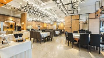 En moderne restaurant med flere spiseborde og stole, en murstensvæg og en lysekrone.