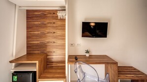 Ein modernes Badezimmer mit einem Holzwaschtisch, einem integrierten Waschbecken und einem an der Wand befestigten Fernseher.