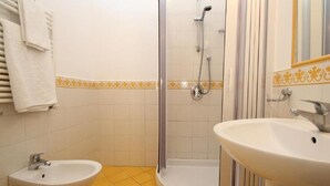 Ein Badezimmer mit zwei Waschbecken, einer Dusche und einem Spiegel.