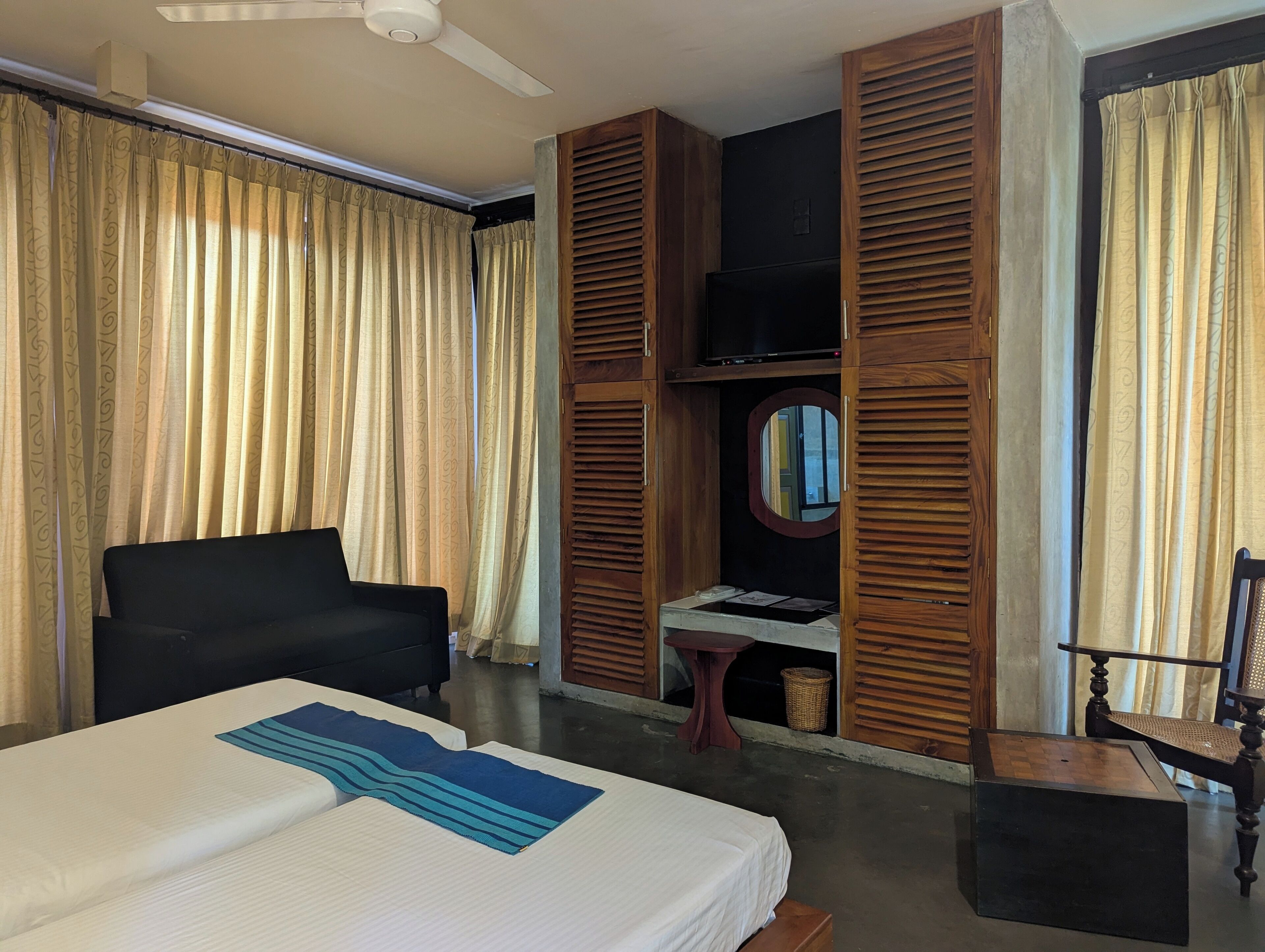 Una habitación de hotel con una cama, un escritorio, una silla, un televisor y paneles de madera.