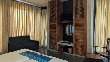 Una habitación de hotel con una cama, un escritorio, una silla, un televisor y paneles de madera.