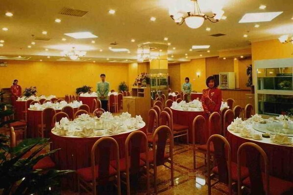 A banquet hall with round tables set for a formal event, featuring a warm color scheme and modern lighting. - Harmony (Beijing)