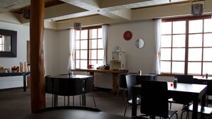 A dining area with tables and chairs, a water dispenser, and a clock on the wall. - Hakuba House (Hakuba)