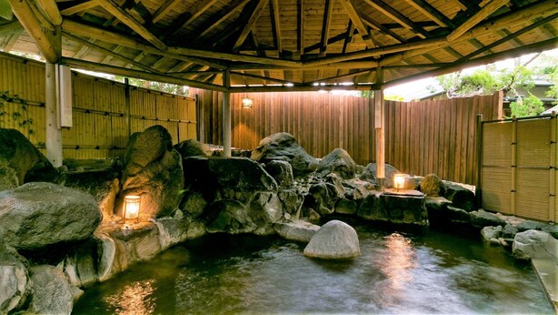 A traditional Japanese onsen with a wooden roof, stone bath, and a bamboo fence. - Ureshino Onsen Ureshino Motoyu (Ureshino)