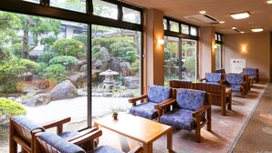 A traditional Japanese-style room with tatami mats, wooden furniture, and a view of a garden with rocks and trees. - Ureshino Onsen Ureshino Motoyu (Ureshino)