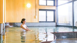 A person in a large indoor swimming pool with wooden walls and large windows. - Ureshino Onsen Ureshino Motoyu (Ureshino)