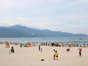 A crowded beach with people, umbrellas, and boats. - Ocean Haven Hotel (Da Nang)
