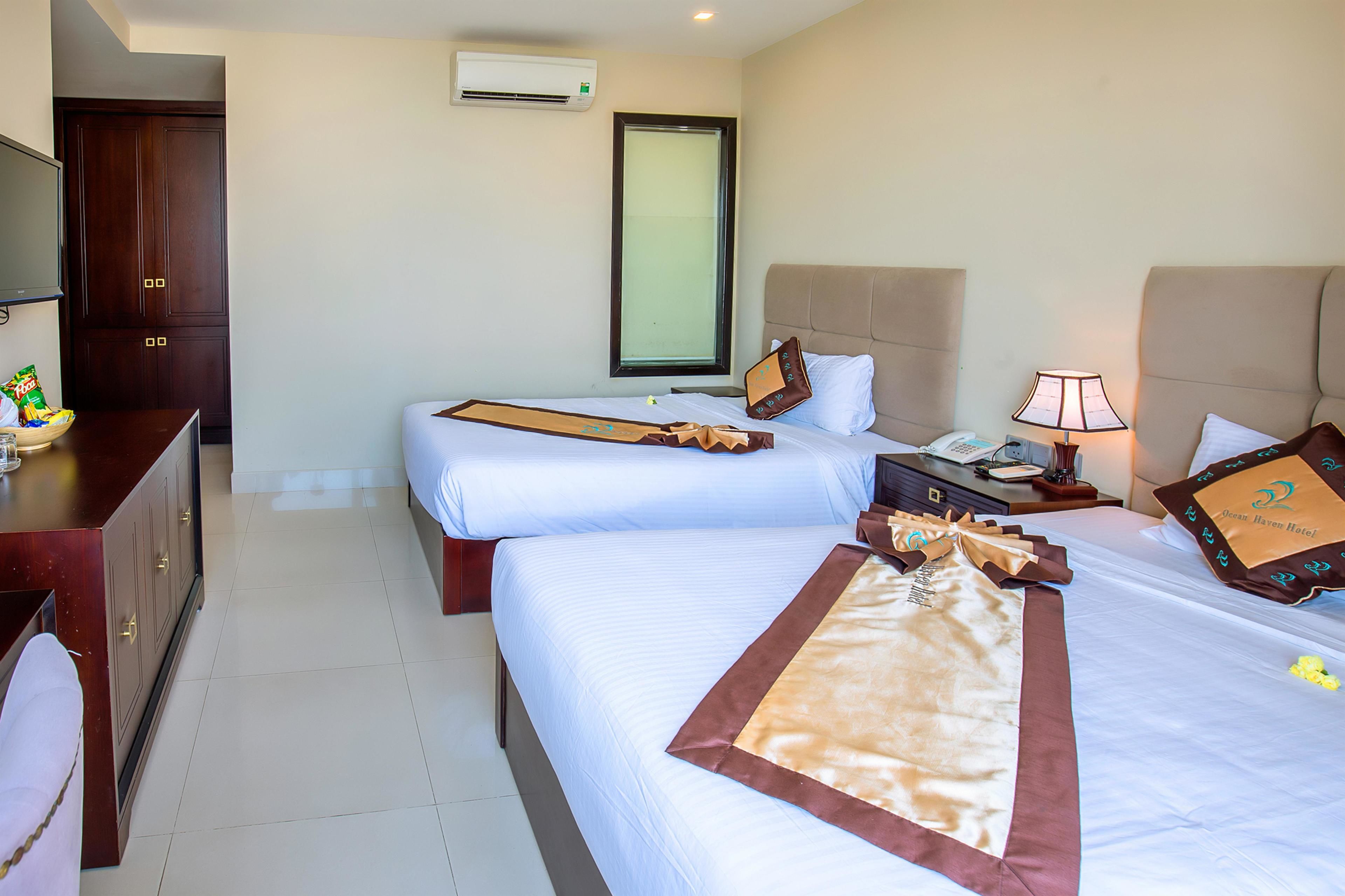 A hotel room with two beds, a TV, a desk, and a wardrobe.