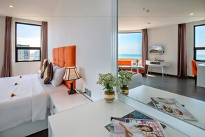 Une chambre d’hôtel équipée d’un lit, d’une table de chevet, d’une lampe et offrant une vue sur la ville grâce à de grandes fenêtres.