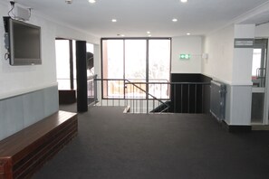 Un hall d’entrée spacieux avec un escalier menant à l’étage supérieur, une grande fenêtre donnant sur les arbres et un téléviseur à écran plat fixé au mur.
