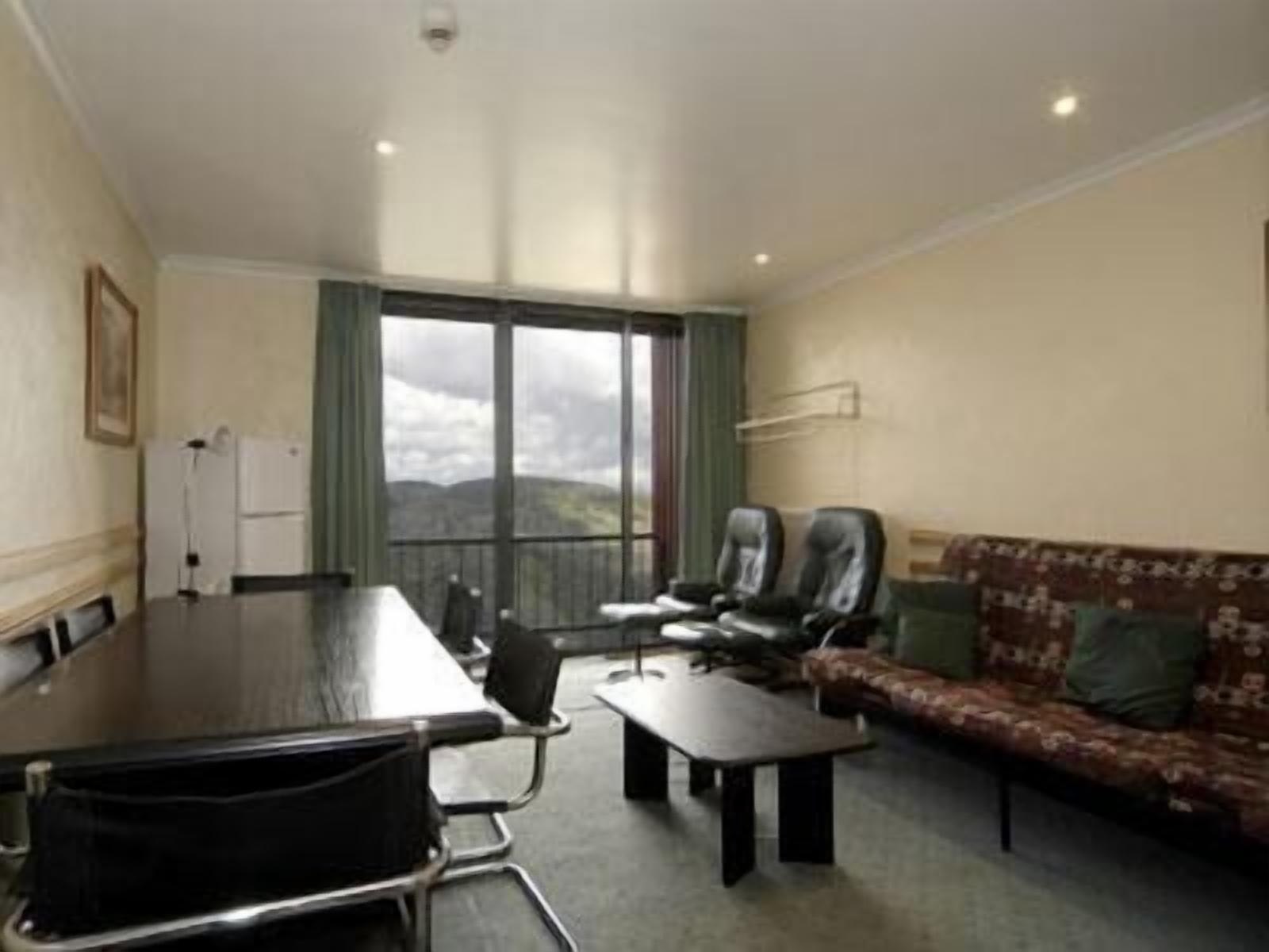 A room with a large table, two chairs, a sofa, and a view of the outdoors.