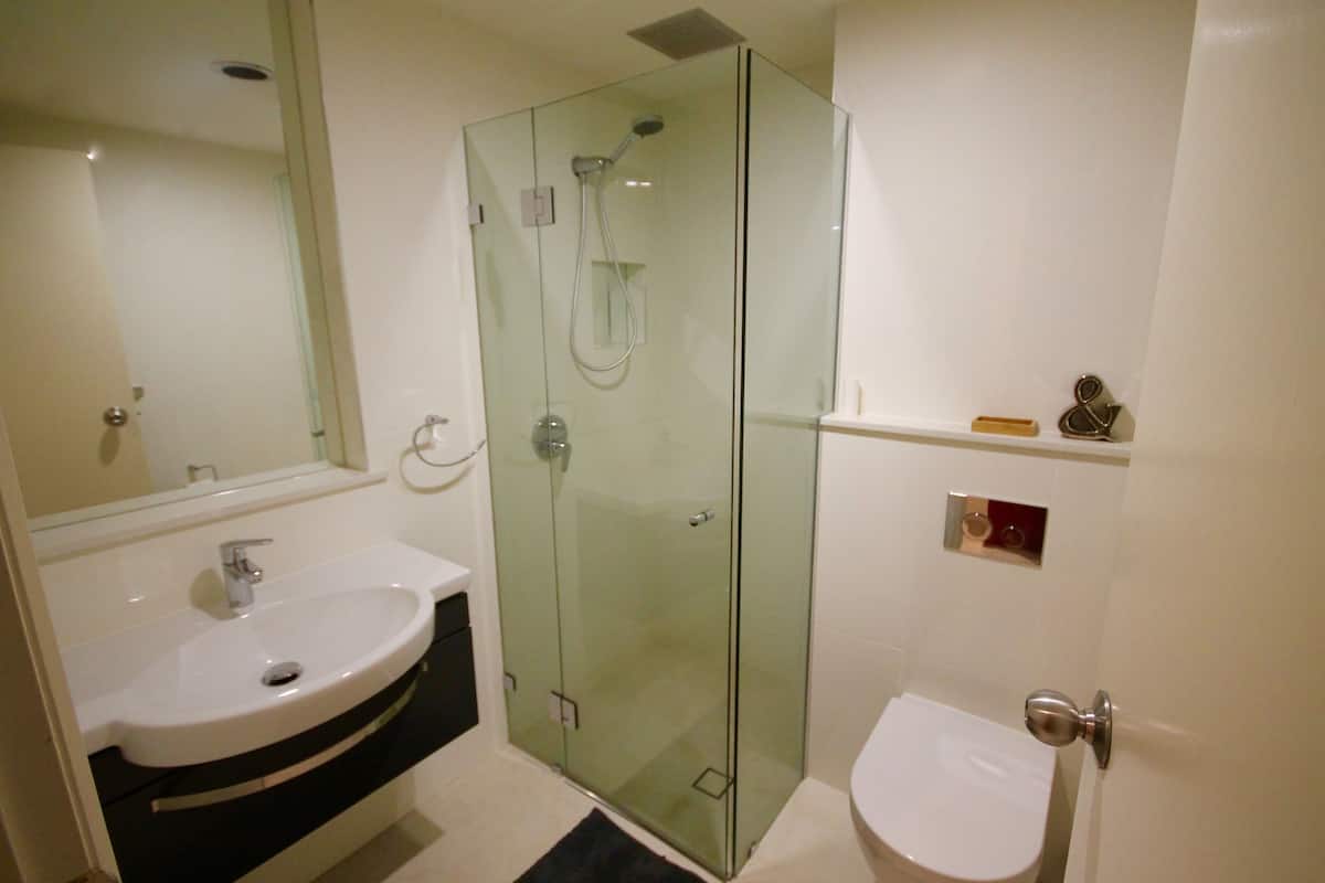 A modern bathroom with a glass-enclosed shower, a white sink, and a toilet.