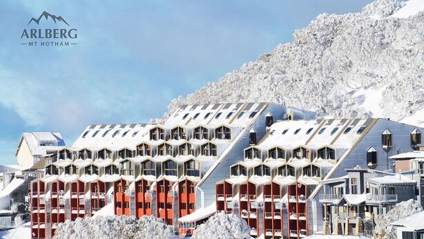 A hotel with multiple hexagonal rooms arranged in a stepped formation, set against a snowy mountain backdrop. - Arlberg Hotham (Hotham Heights)