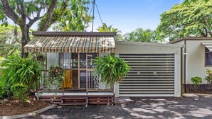A small, single-story building with a striped awning, a front door, and a garage door.