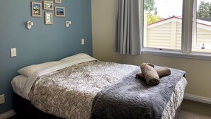Un dormitorio con una cama, una ventana con cortinas e iluminación fijada a la pared.
