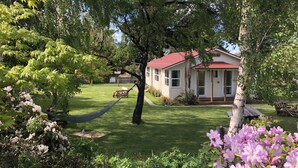 Una casa con techo rojo, rodeada de abundante vegetación y plantas florecientes.