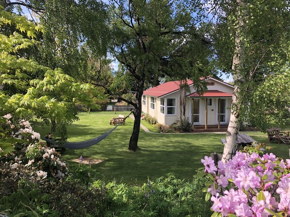 A house with a red roof, surrounded by lush greenery and flowering plants.