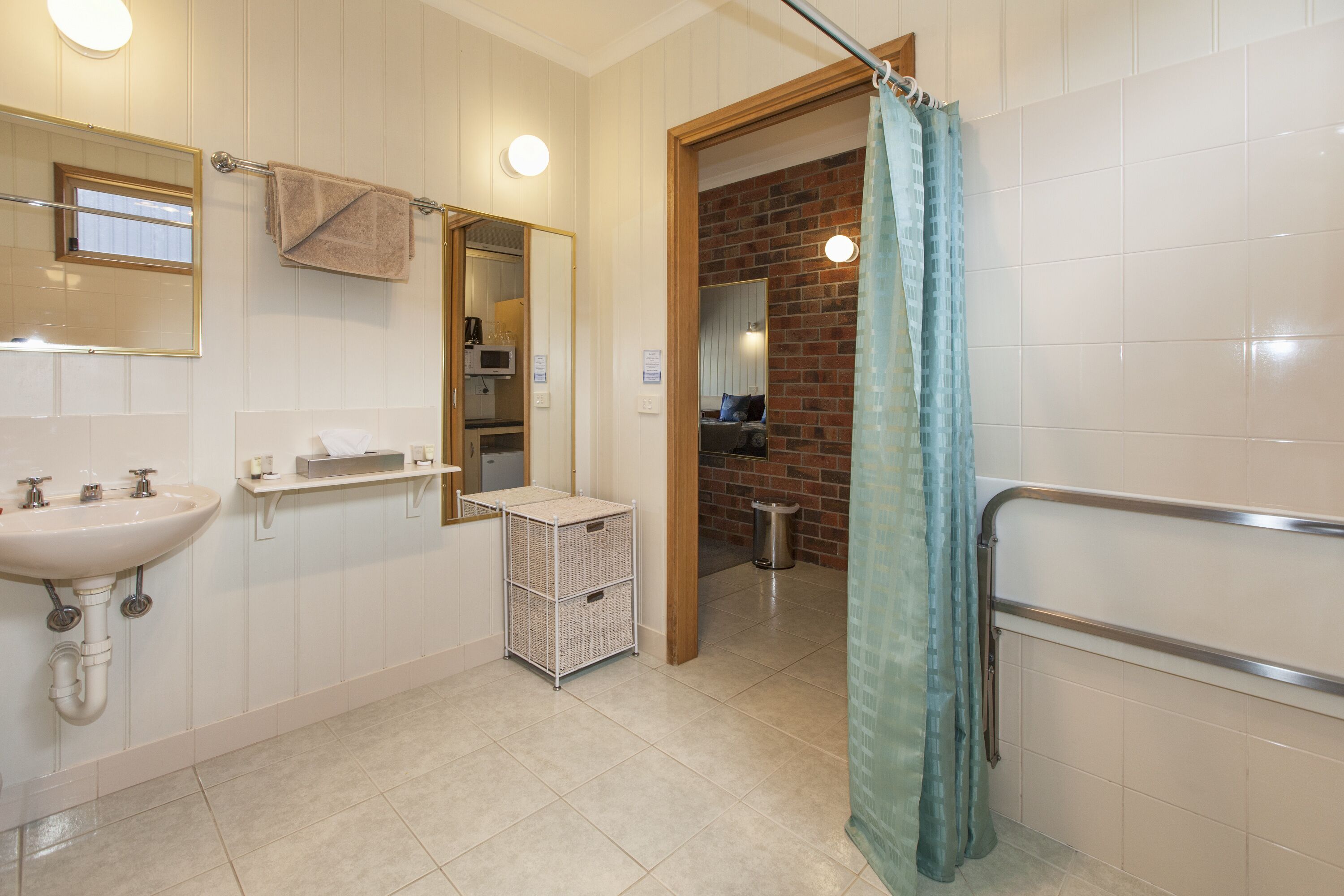 Un baño con lavamanos, espejo, toallero y zona de ducha con cortina.