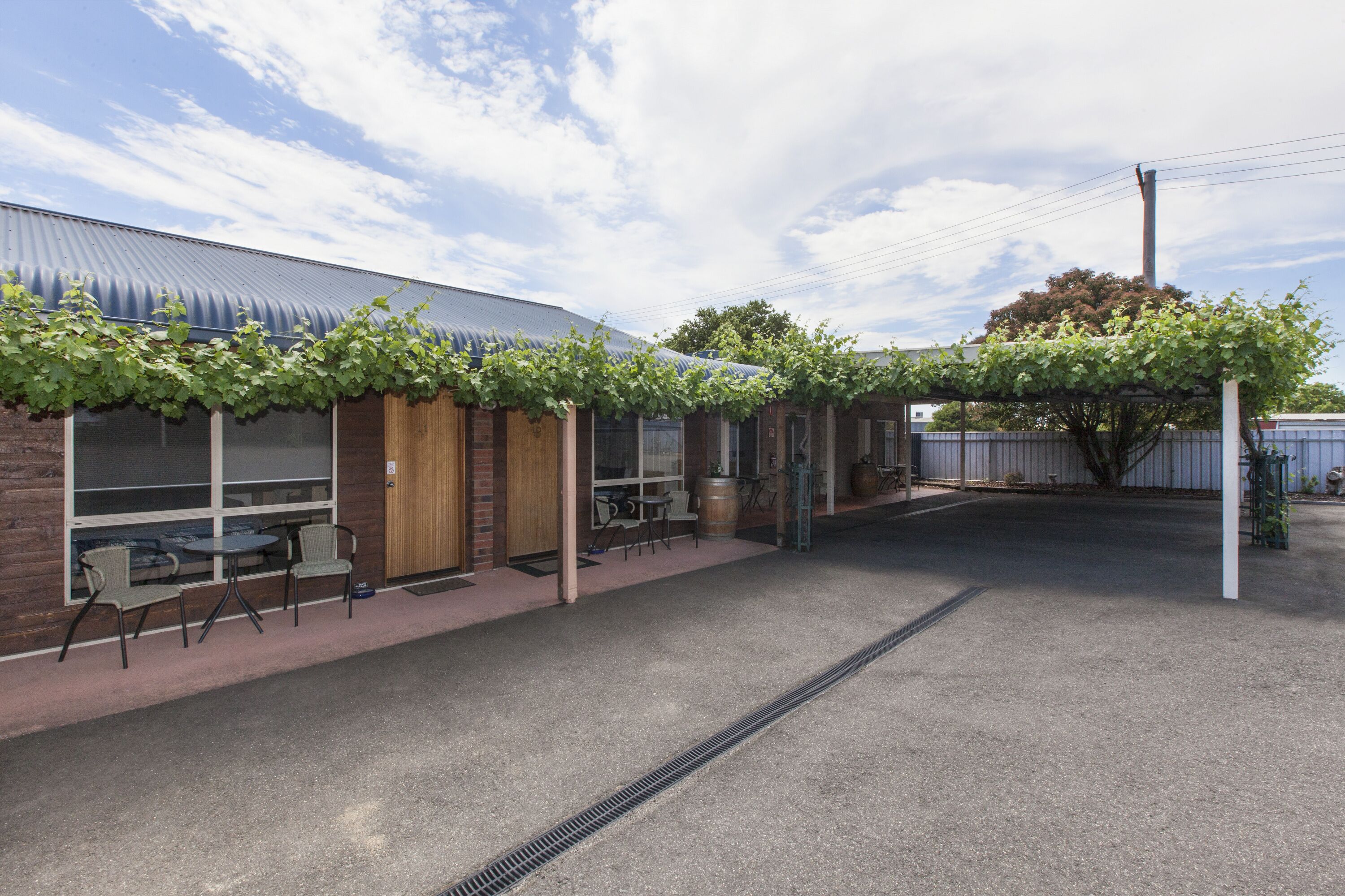 A building with a covered patio area, outdoor seating, and a tree.