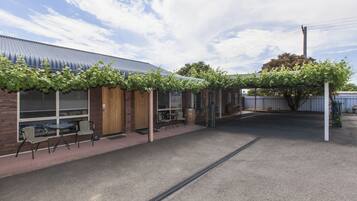 A building with a covered patio area, outdoor seating, and a tree.
