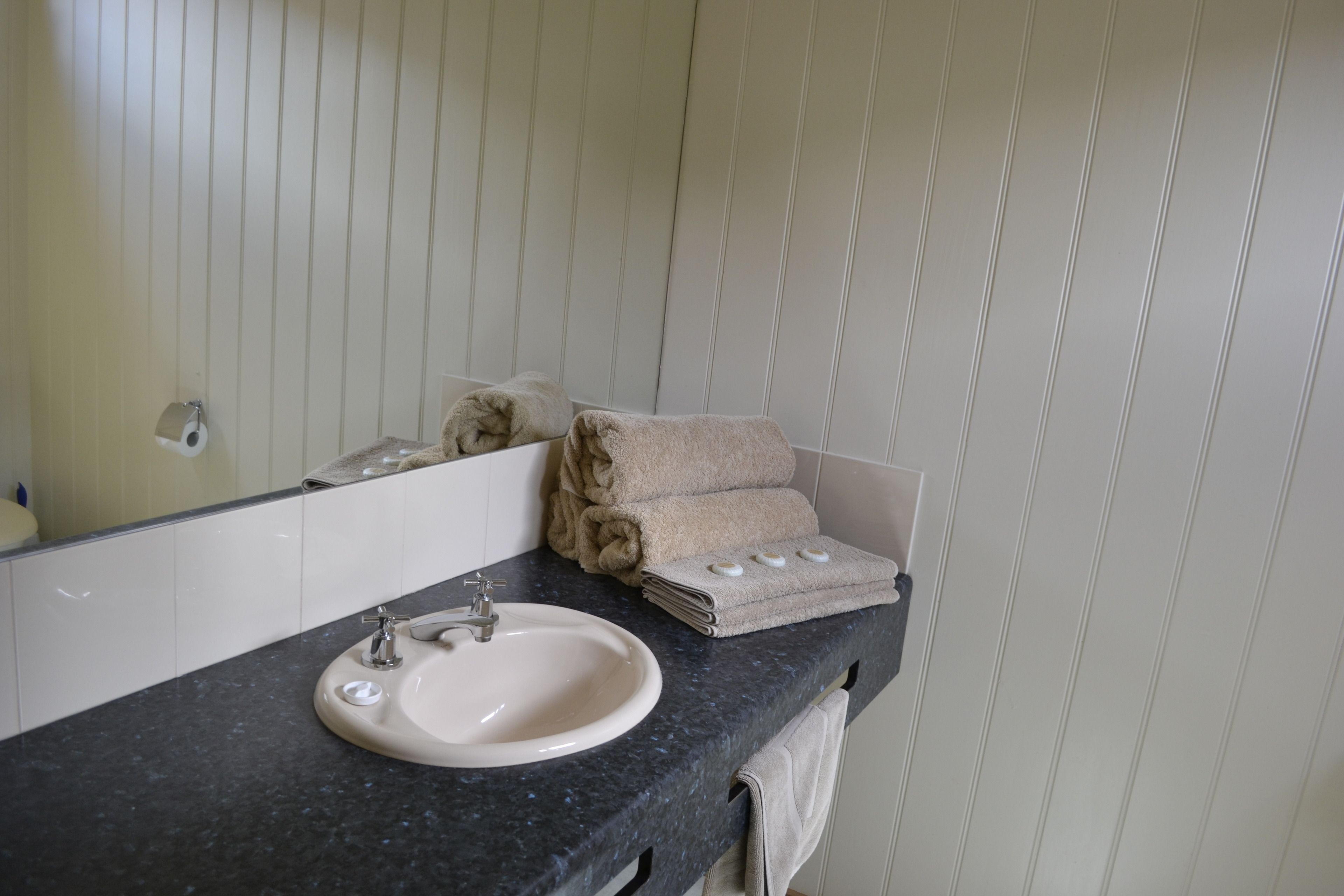 Un baño con lavamanos, espejo y toallas.
