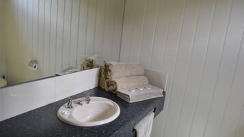 Un baño con lavamanos, espejo y toallas.