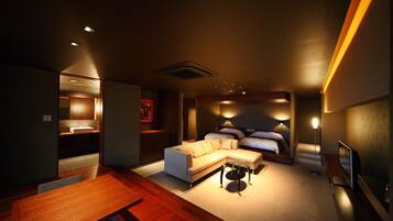 A modern hotel room with a sofa, a bed, a TV, and a desk.