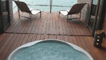 Un jacuzzi en una terraza de madera con vista al mar y una isla.