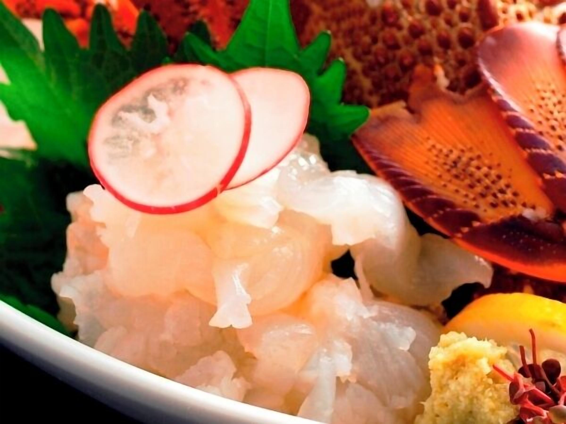 A bowl of seafood with shrimp, scallops, and a lemon wedge.