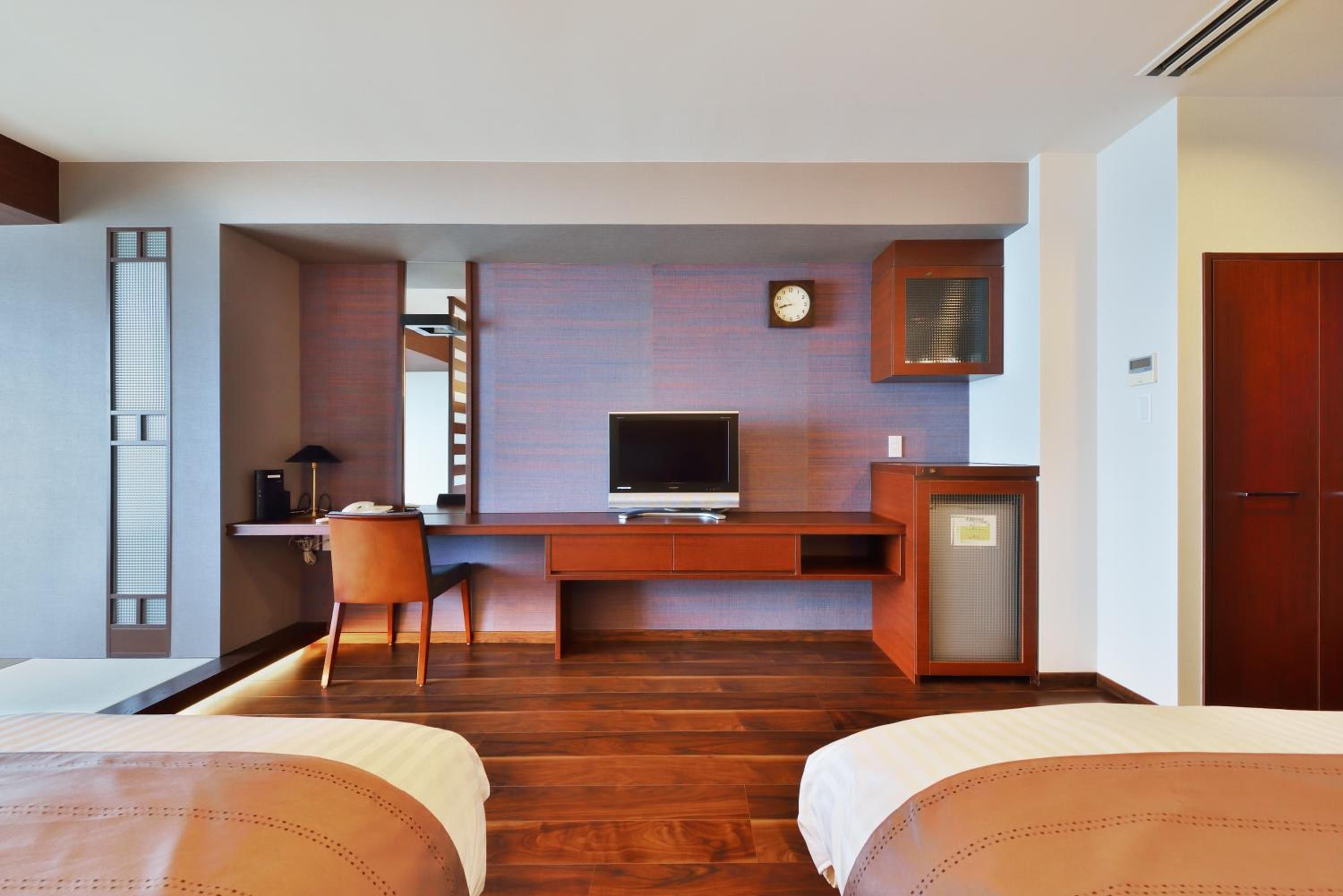 Ein Hotelzimmer mit einem Holztisch, einem Fernseher, einer Uhr und einem Kleiderschrank.