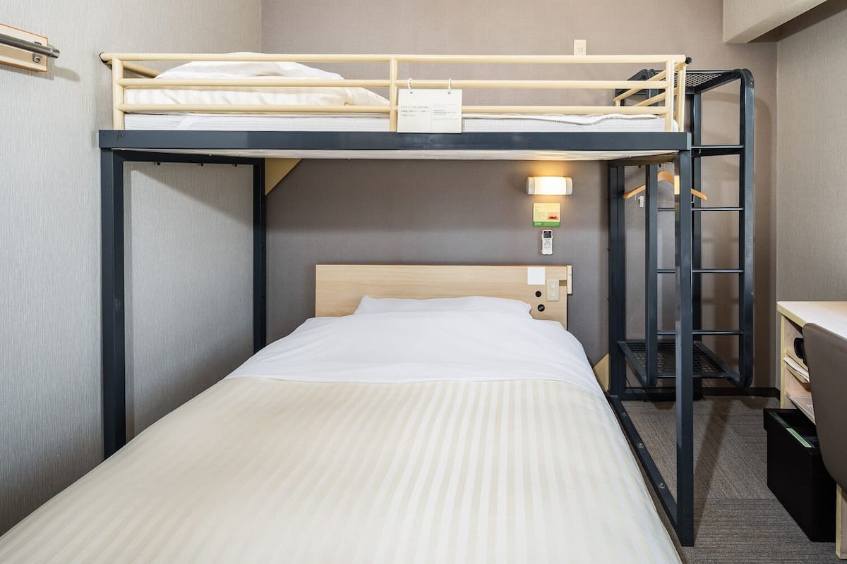 A bunk bed room with a desk and a lamp.