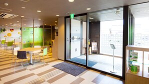 A modern hotel lobby with a check-in counter, seating area, and a glass door leading to the reception. - Super Hotel Fuji Inter (Fuji)