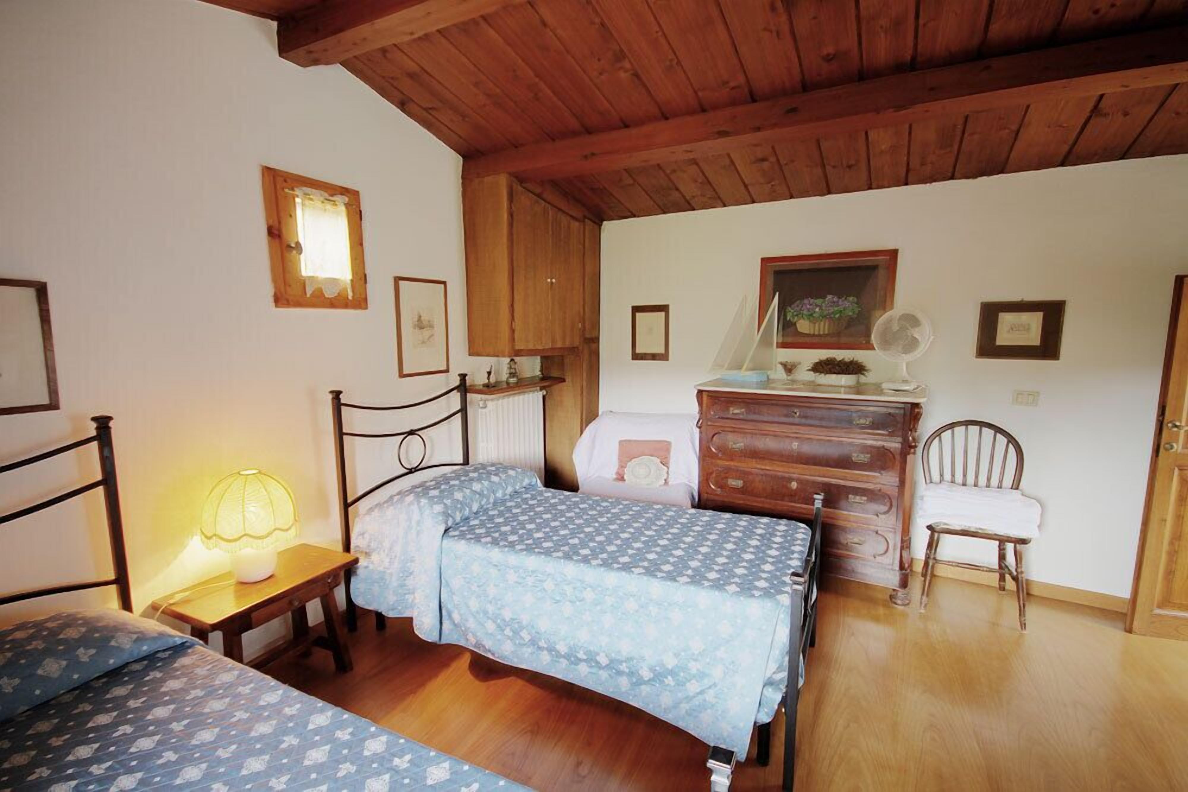 A bedroom with two beds, wooden furniture, a dresser, and a fan.